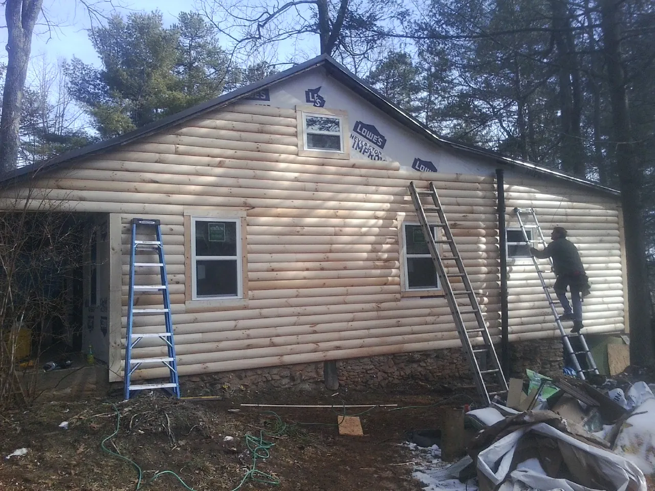 Ladders set against fresh log siding during an exterior remodel in Newport